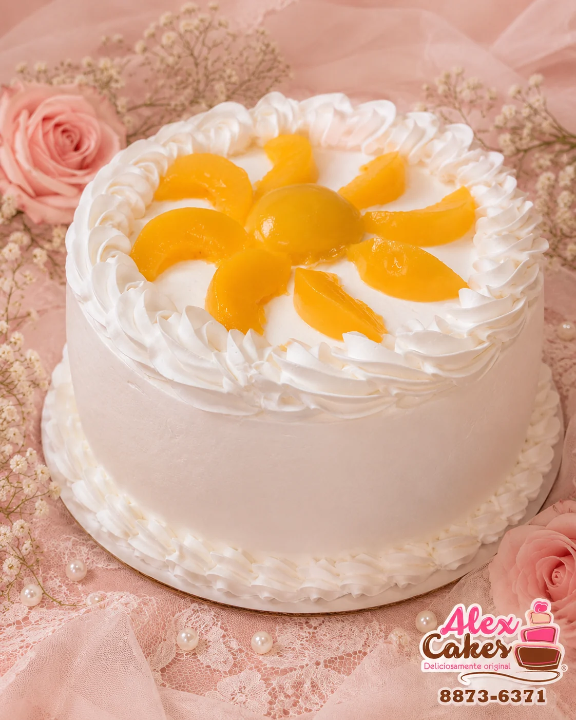 Pastel artesanal blanco con decoración de frutas sobre un mantel rosado